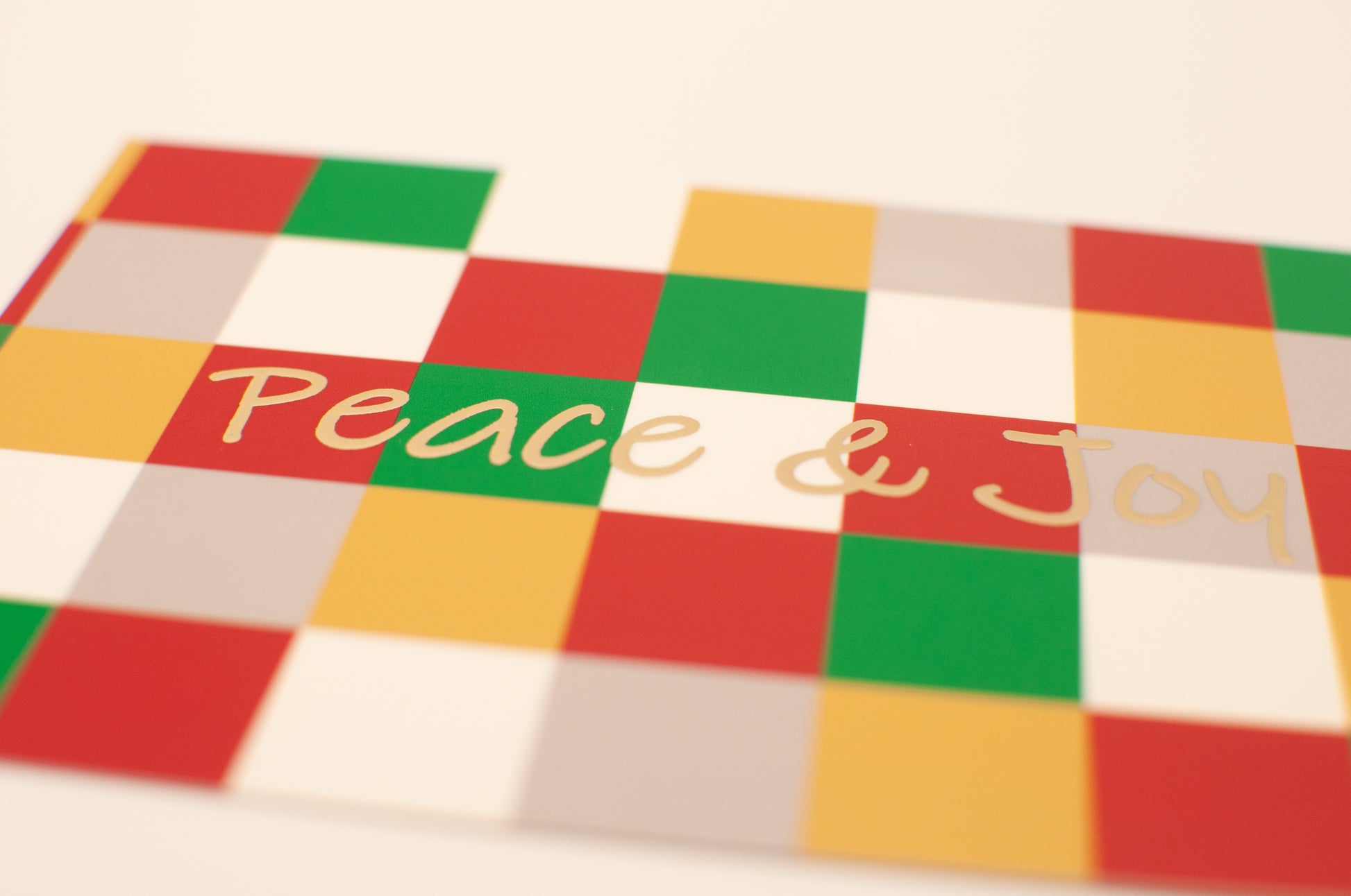Colorful checkered pattern with 'Peace & Joy' text on a white background